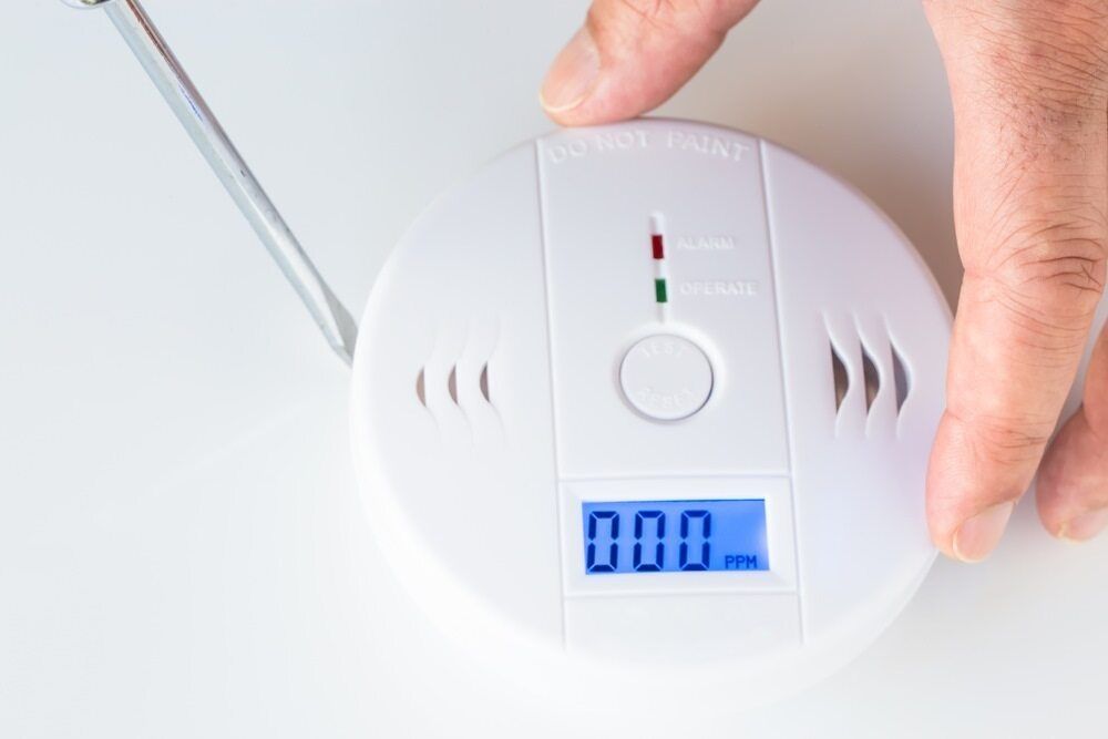 A Person Is Holding A Screwdriver Next To A Smoke Detector — Cool & Secure In Warana, QLD