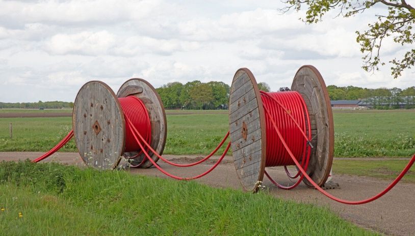 Two Wooden Spools Filled With Red Wires Are Sitting On The Side Of A Road — Cool & Secure In Noosa, QLD