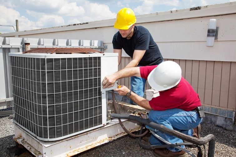 Two Men Are Working On An Air Conditioner On The Roof Of A Building — Cool & Secure In Noosa, QLD