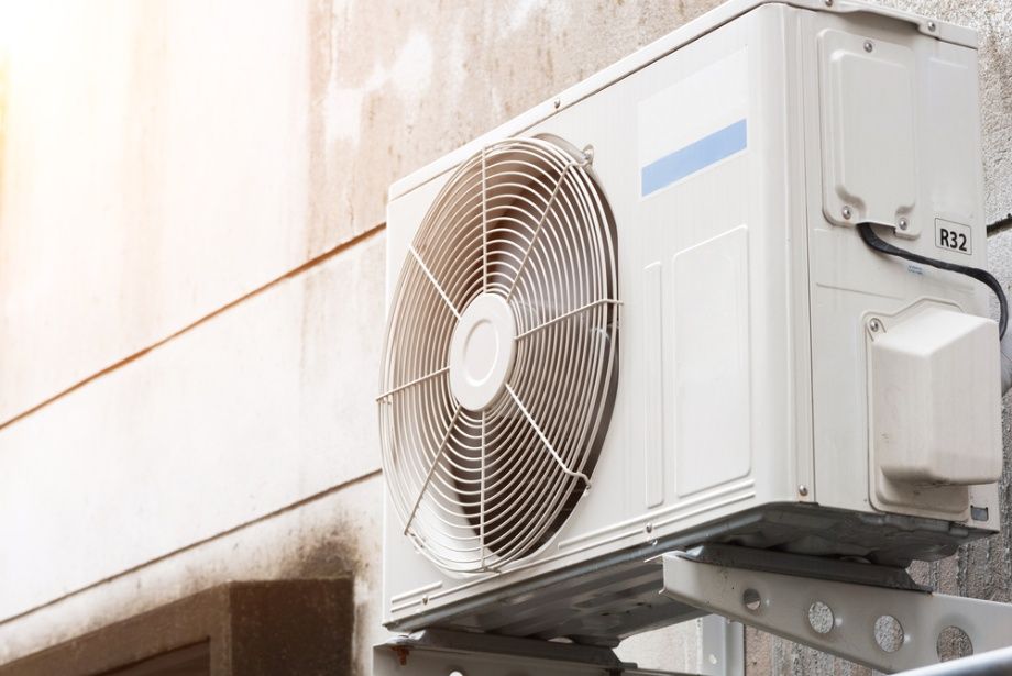 A White Air Conditioner Is Mounted On The Side Of A Building — Cool & Secure In Noosa, QLD