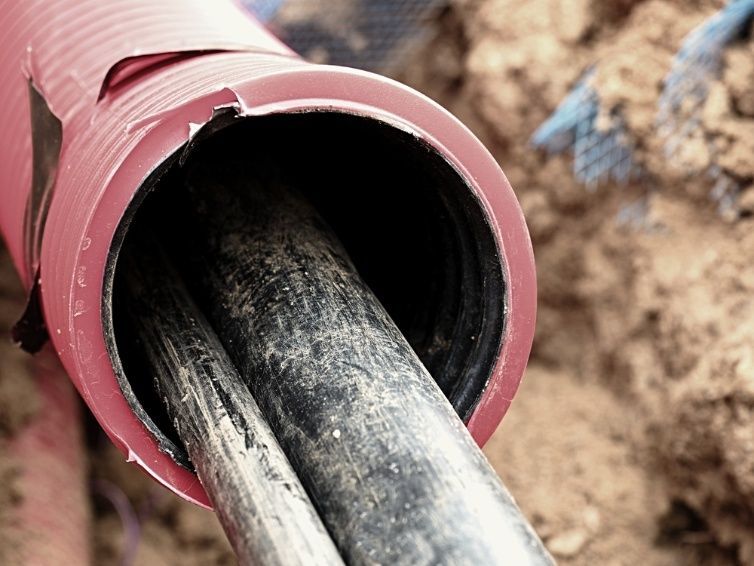 A Close Up Of A Red And Black Pipe In The Dirt — Cool & Secure In Buderim, QLD