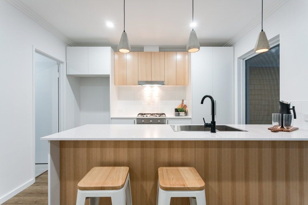 A Kitchen With Wooden Cabinets , White Counter Tops , A Sink And Two Stools — Cool & Secure In Buderim, QLD