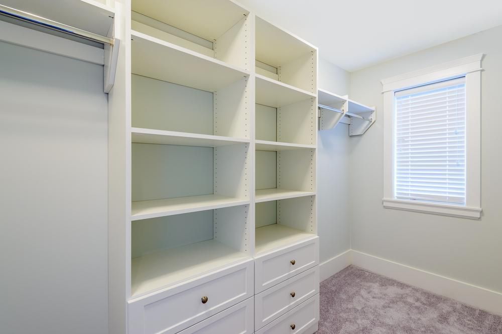 An Empty Walk in Closet With White Shelves and Drawers and a Window — Lennox Build In Bangalow, NSW