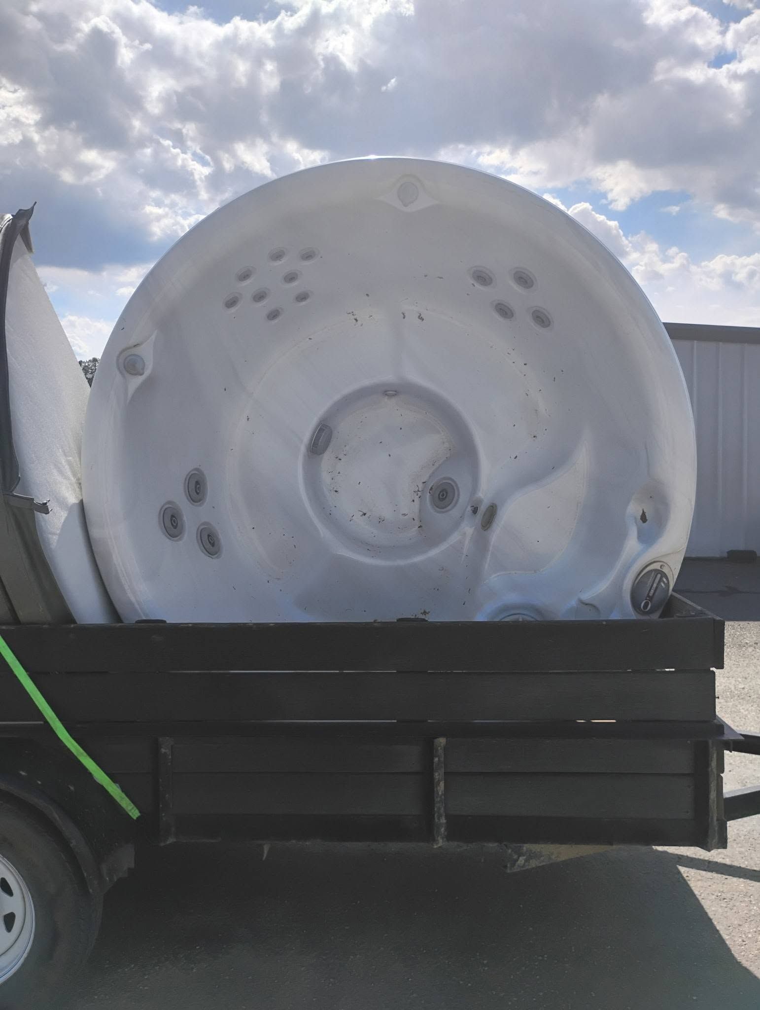 Large white circular industrial part mounted on a trailer or truck bed under a cloudy sky