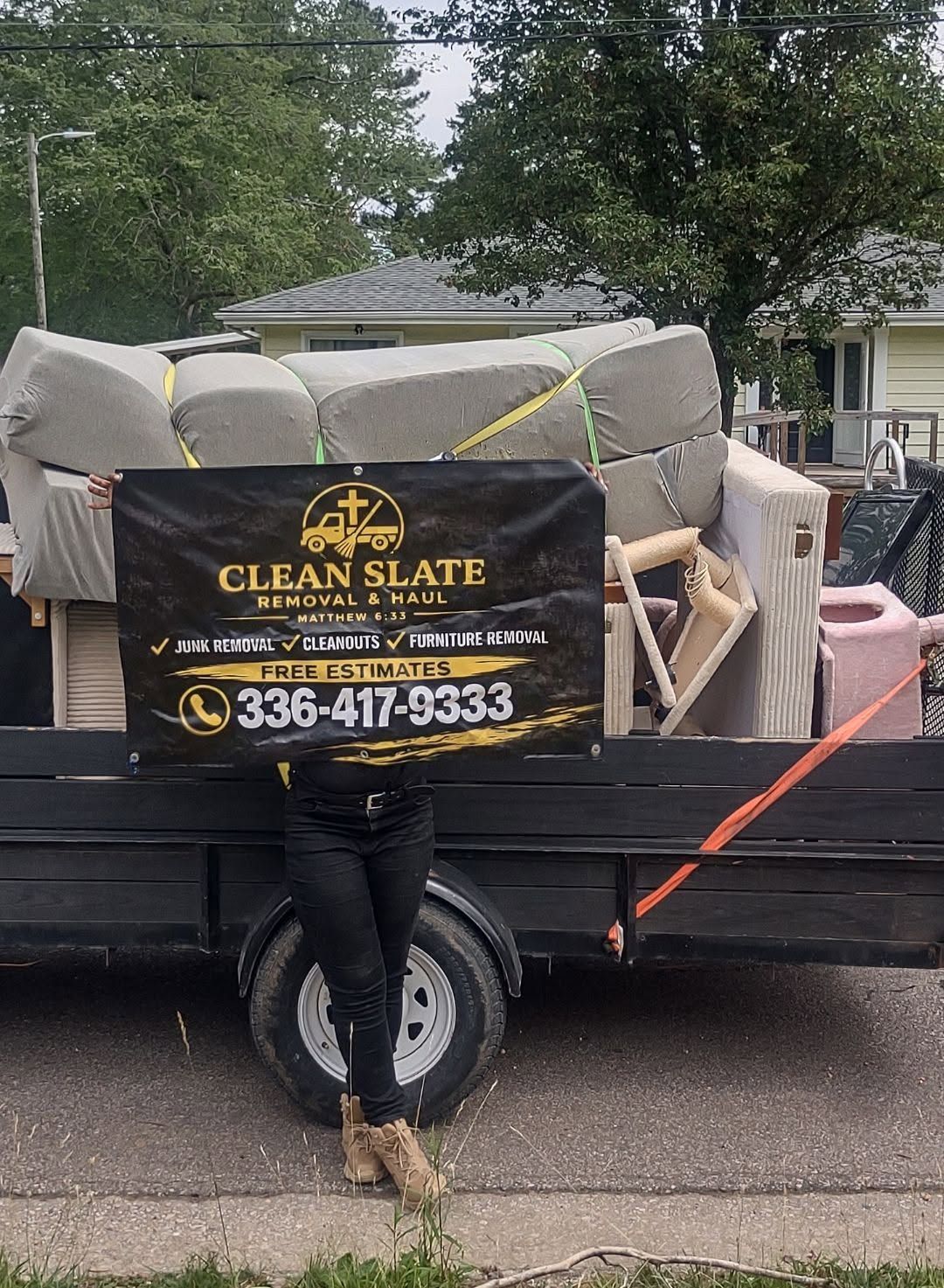 Truck hauling furniture with Clean Slate moving sign on the back, parked on a street.