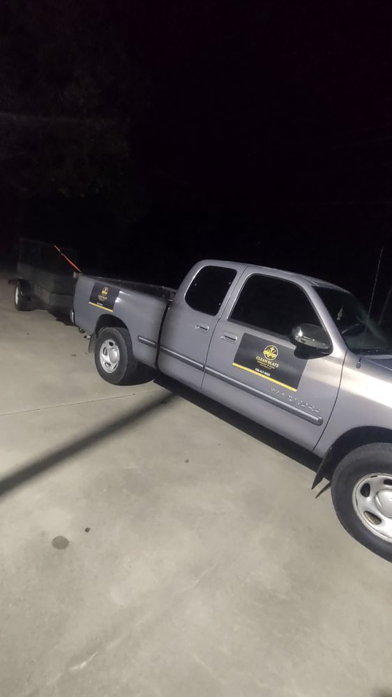 Silver pickup truck parked at night on a concrete driveway near a fence.