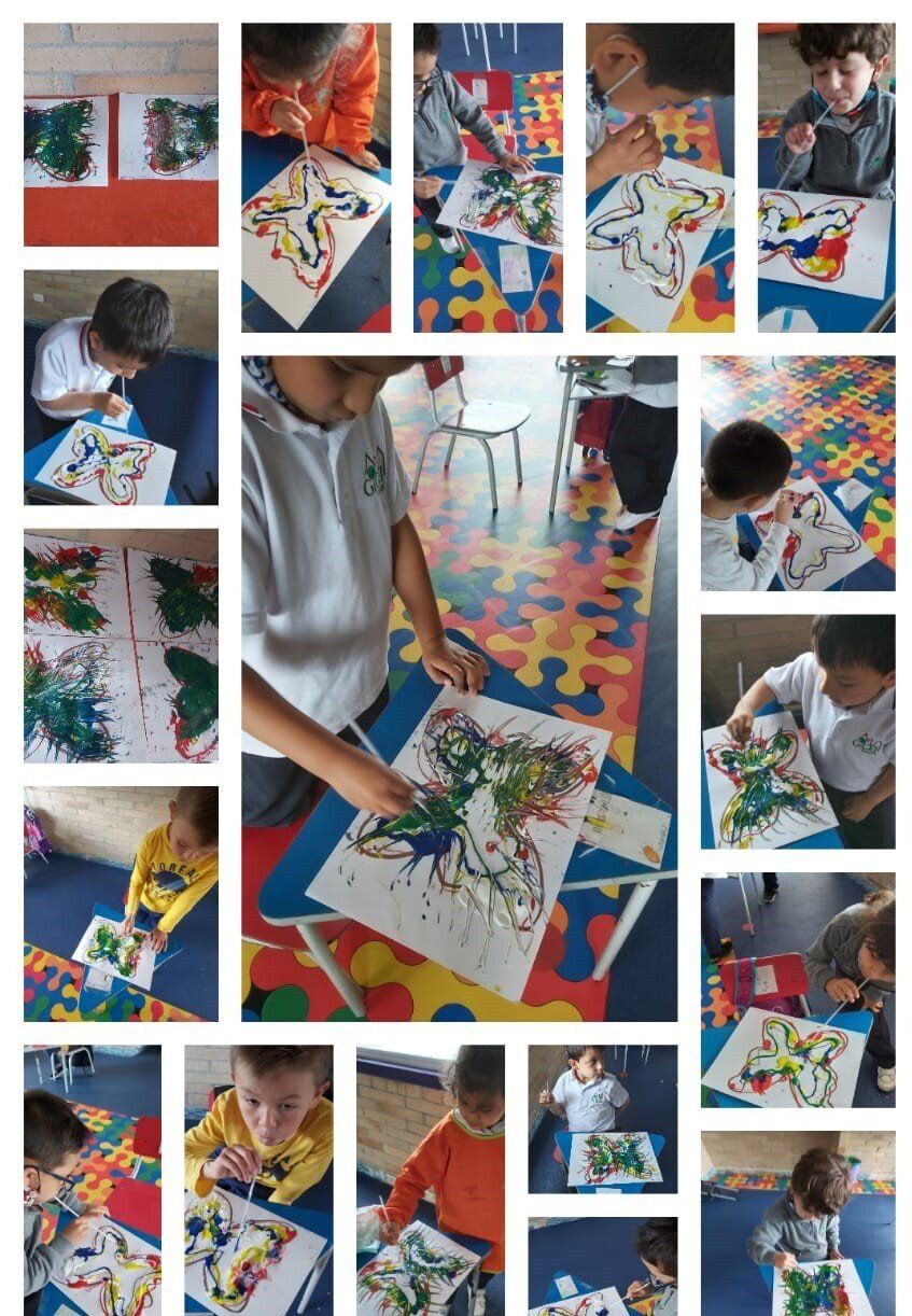 Un niño pinta arte abstracto y colorido sobre una mesa cubierta con muchas obras de arte terminadas.