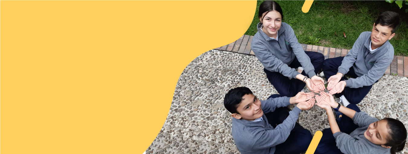 Cuatro compañeros de trabajo en círculo apilando manos sobre un fondo amarillo.