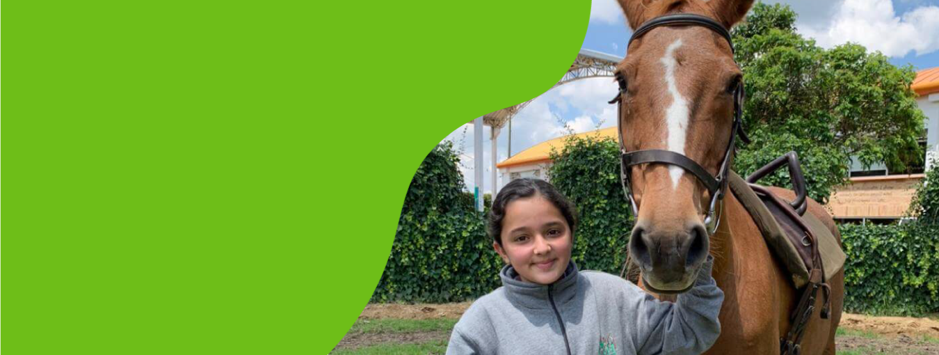 Mujer de pie junto a un caballo marrón al aire libre en una granja.