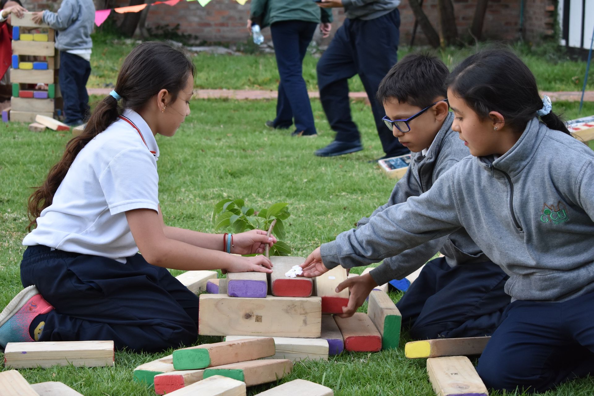Niños construyendo con bloques de madera sobre el césped en un parque.