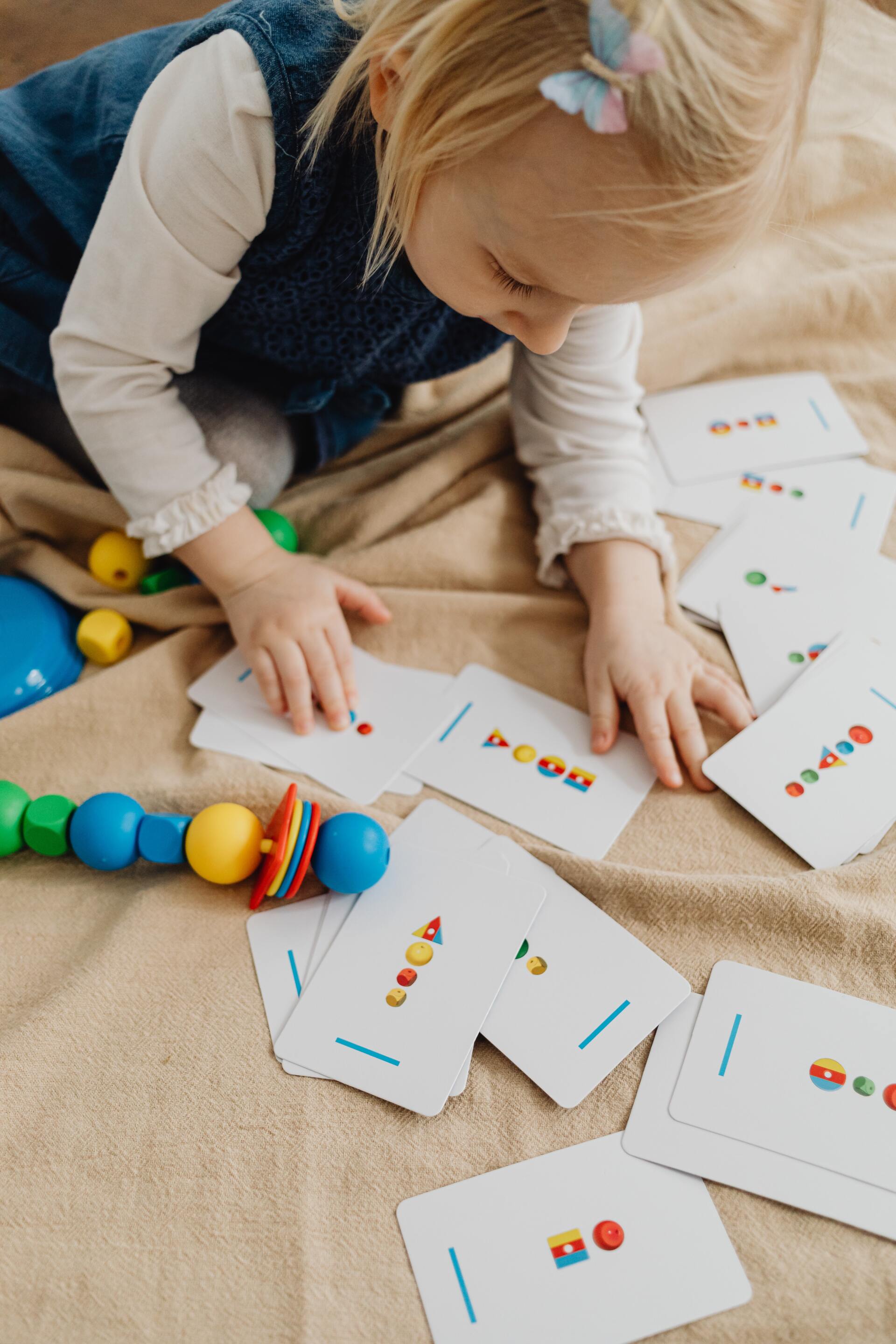 Un niño coloca tarjetas y cuentas de colores en el suelo durante una actividad de aprendizaje práctico.