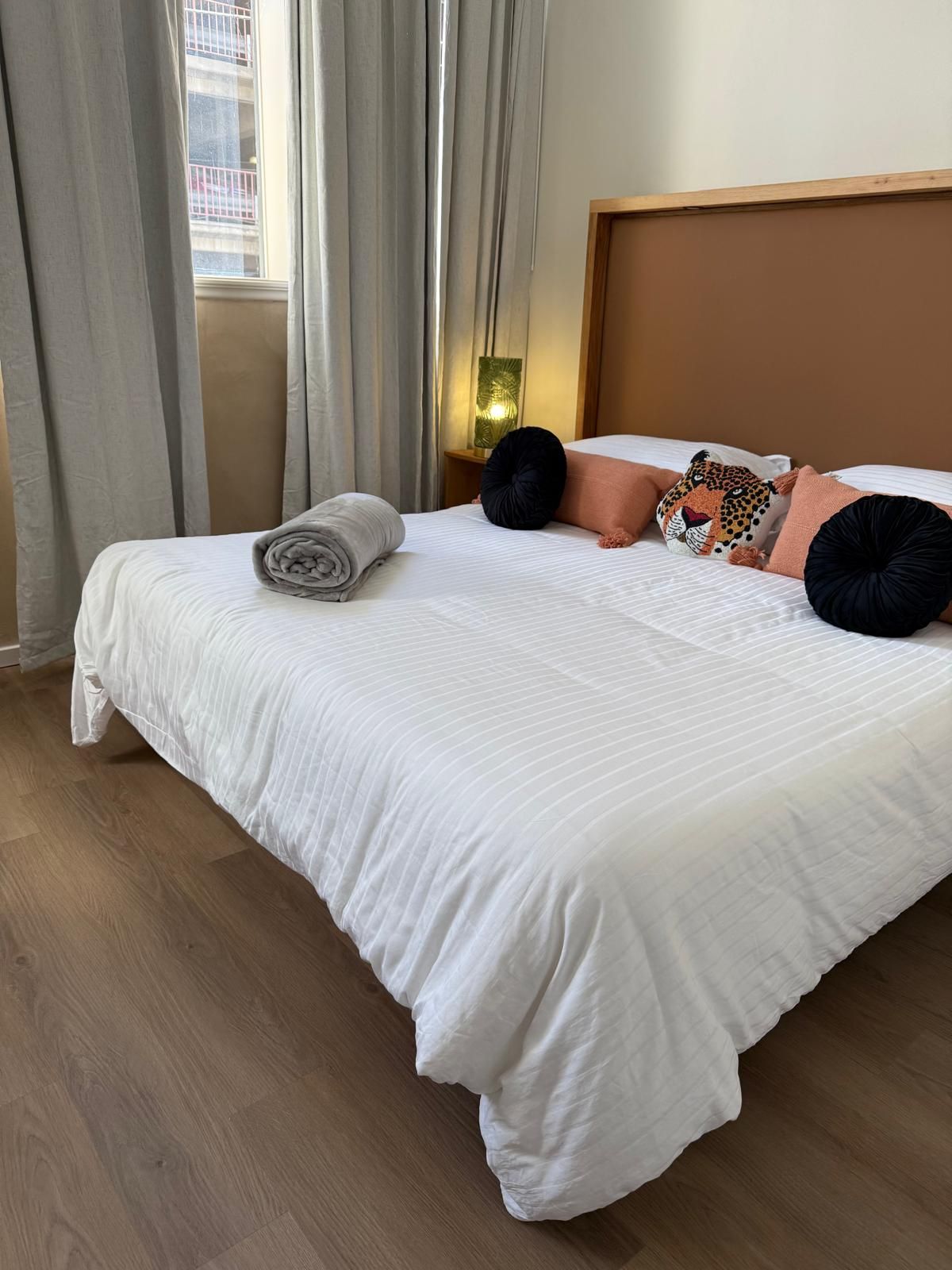 Bedroom with a bed, pillows, a rolled towel, and curtains.