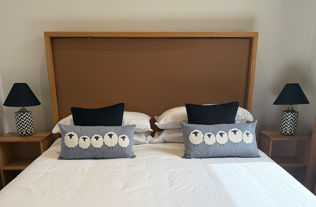 Bedroom with large bed, brown headboard, nightstands, lamps, and decorative pillows.