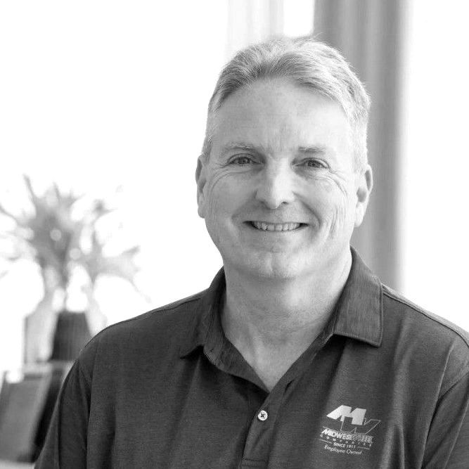 Man in polo shirt smiles at the camera, inside.
