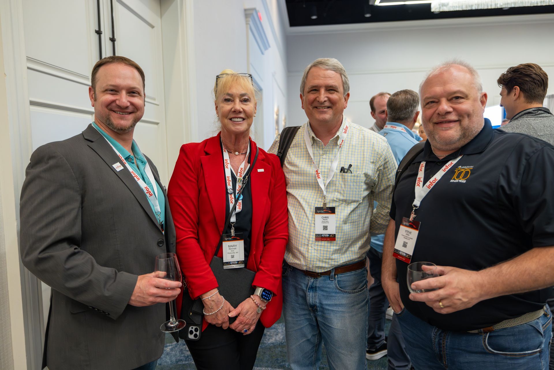 Four people smiling, posing together indoors, in conference setting.