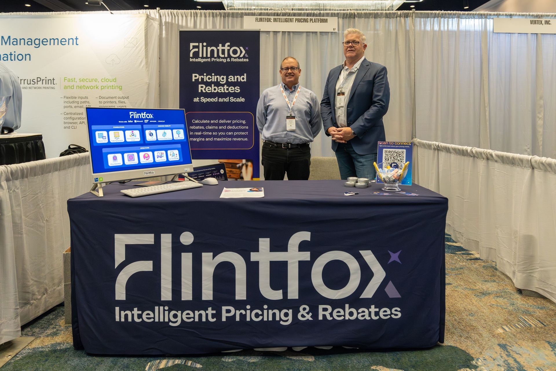 Two men at a trade show booth for Flintfox, an intelligent pricing and rebates software provider.