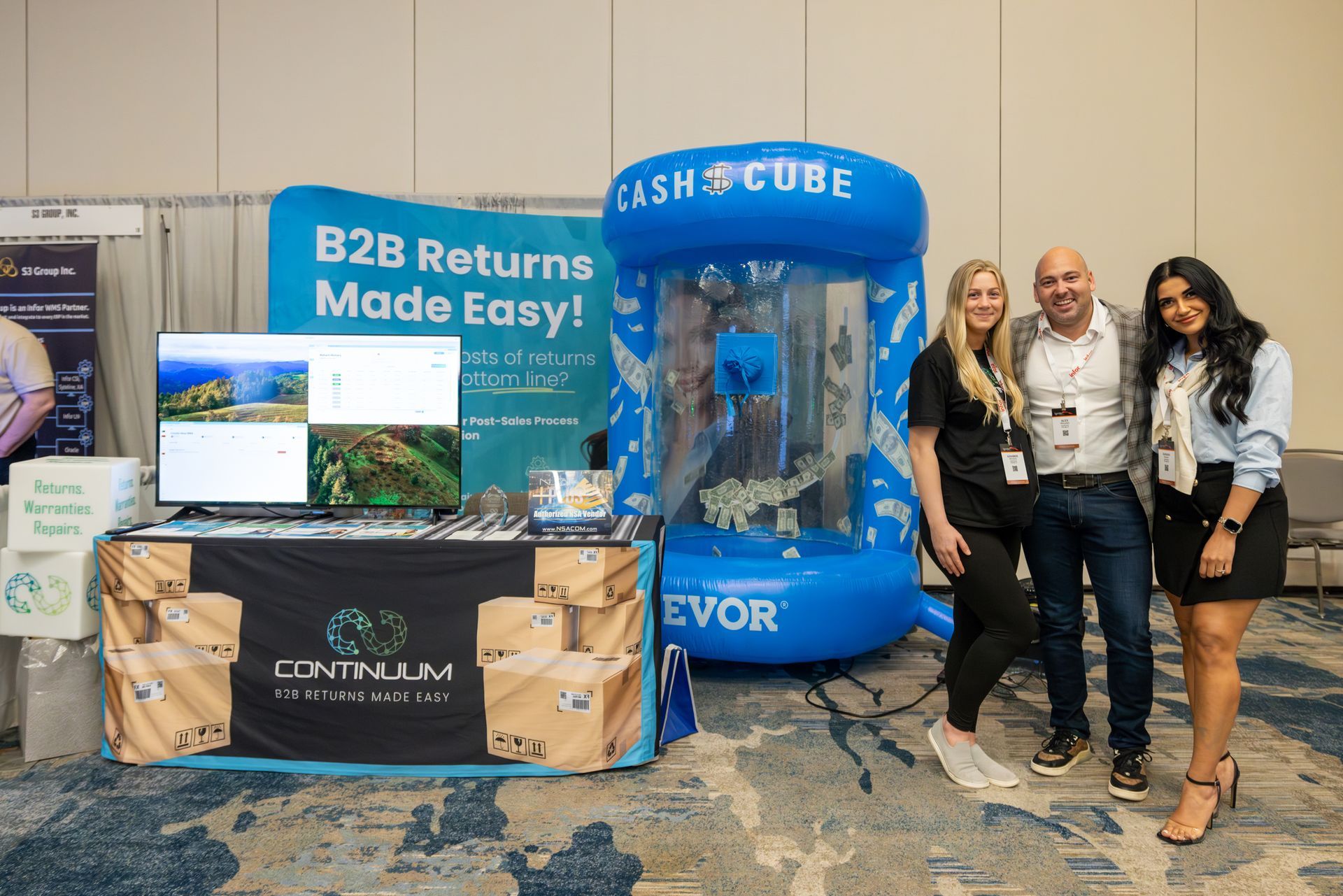 Three people pose at a Contallum booth at a conference, with a 