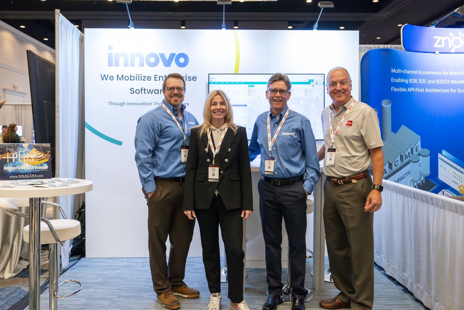 Four people standing at a trade show booth with the Innovo logo. They are smiling.