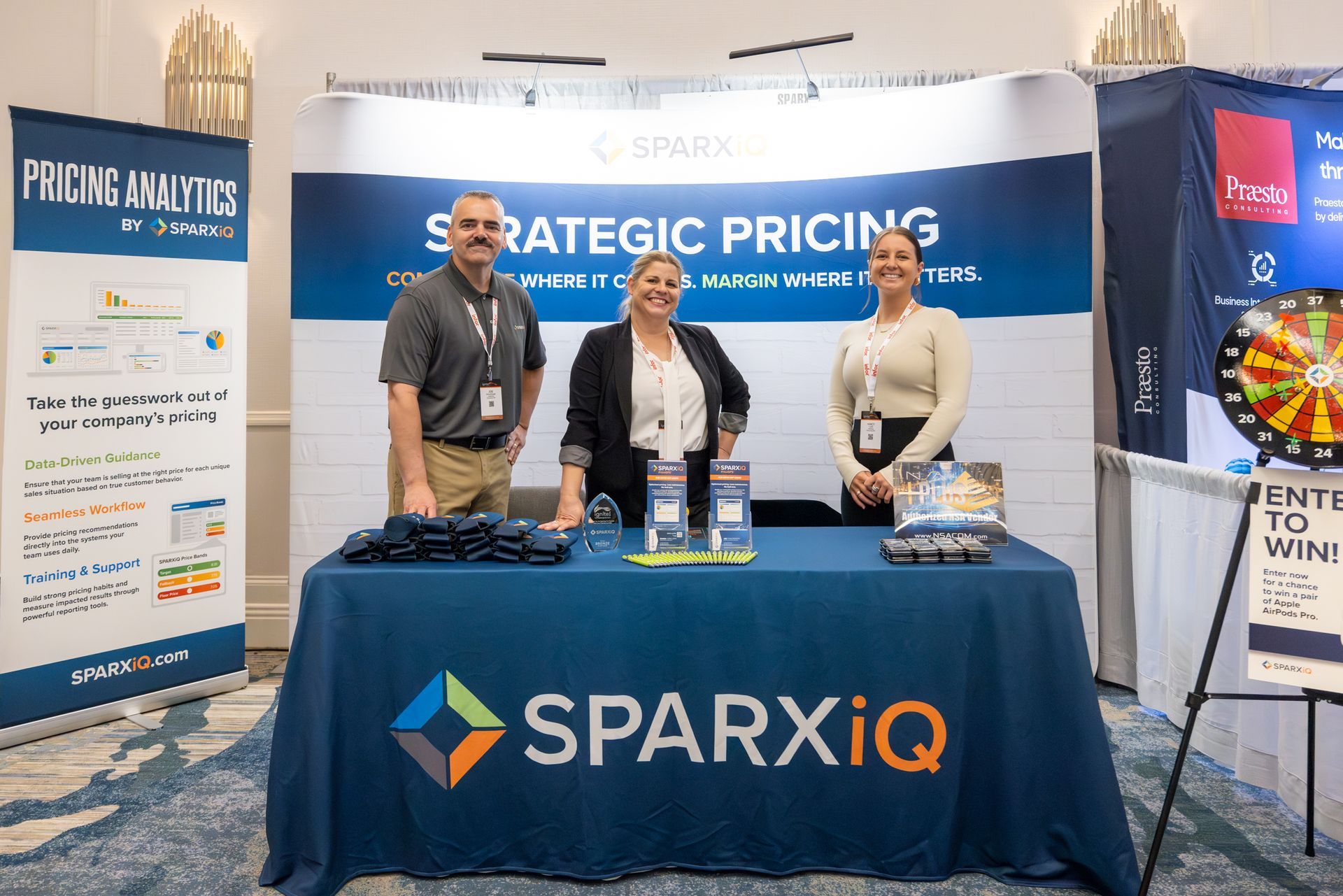 Three people at a trade show booth promoting SparxIQ's 