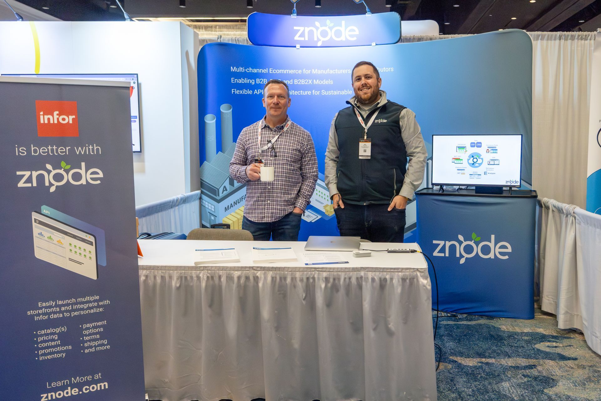 Two men stand at a trade show booth with 