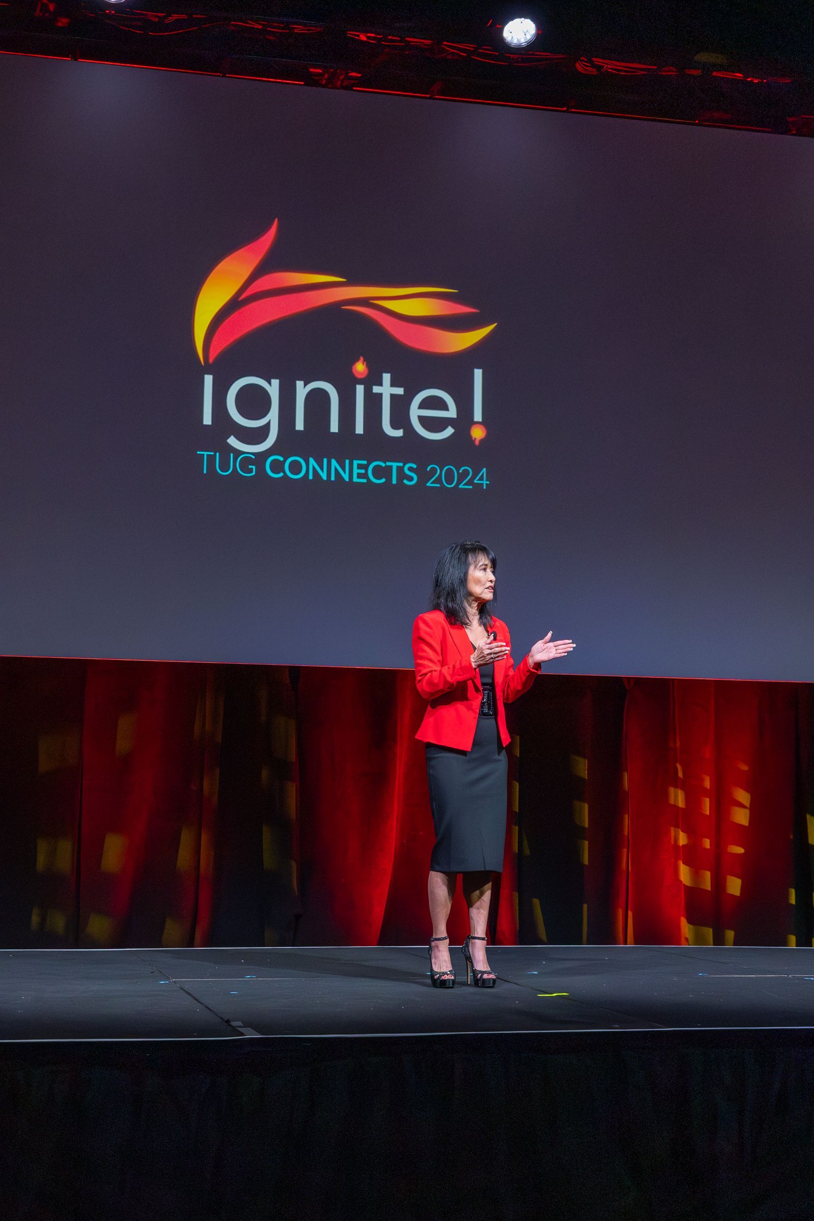Woman speaking on stage at a conference, with 