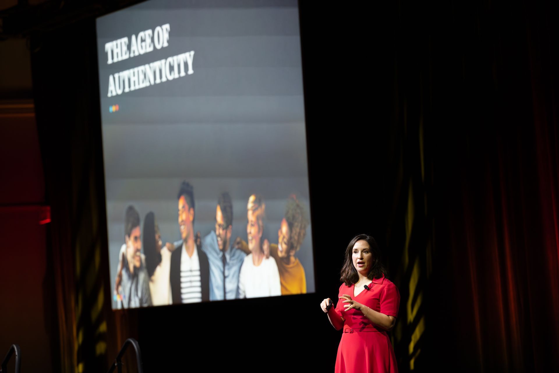 Woman in red dress presents in front of a screen. Screen shows 