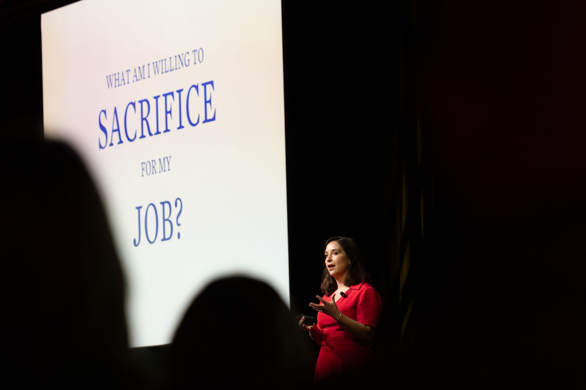 Woman giving a presentation on a stage with the question 