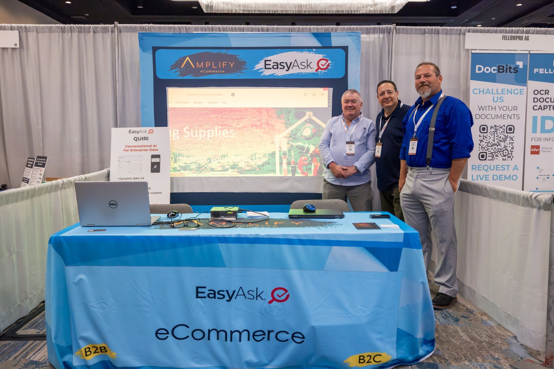 Three men stand at a trade show booth with 