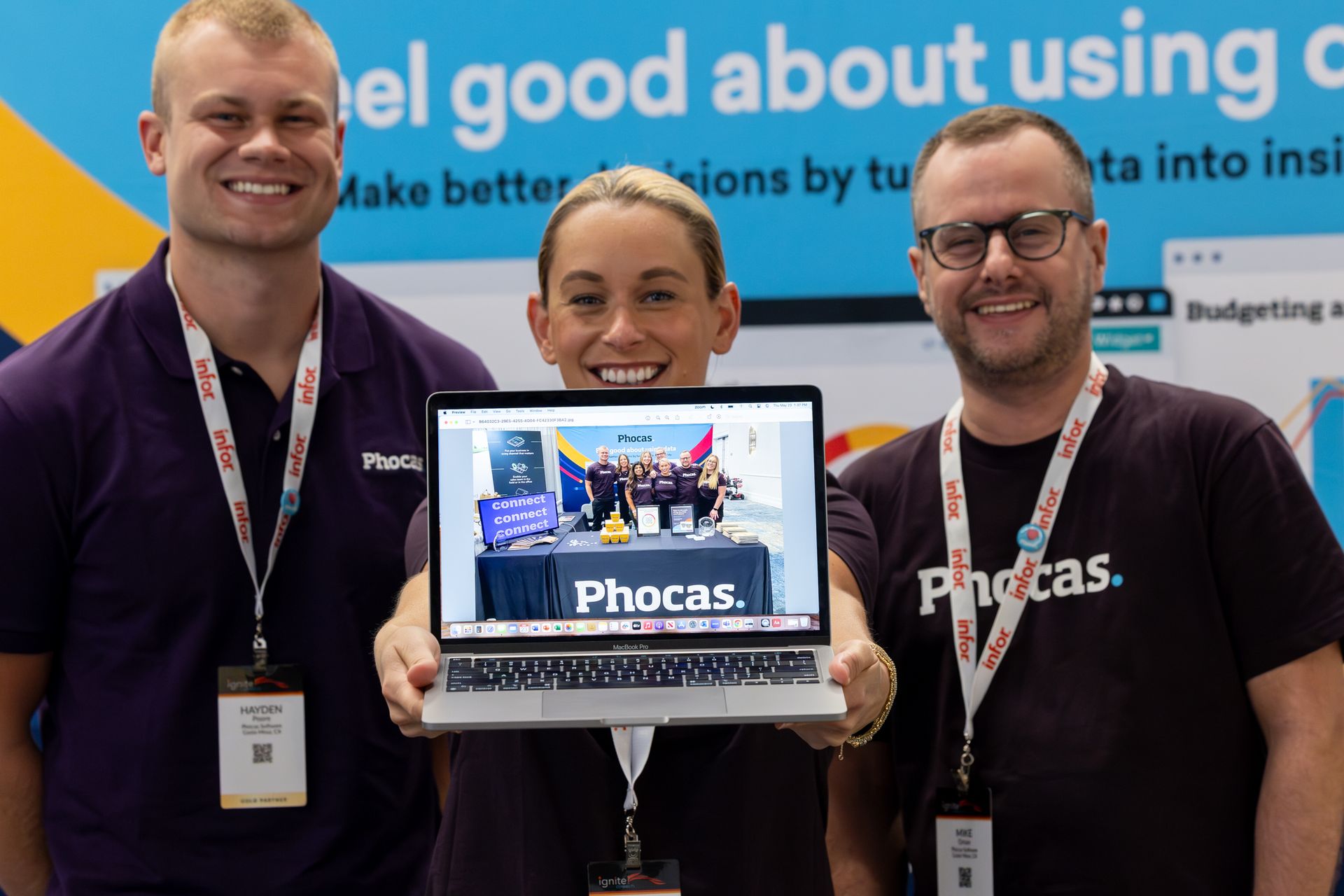 Three people holding a laptop, smiling at the camera, promoting 