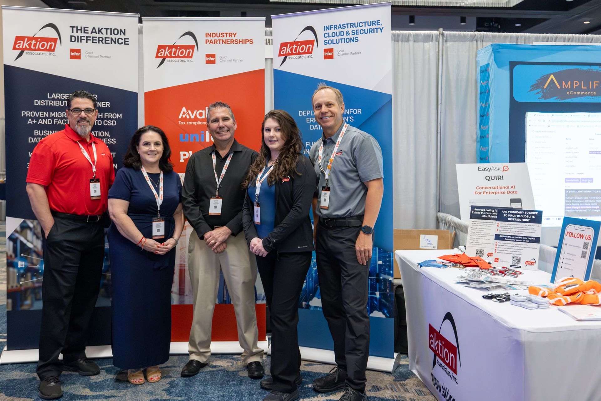 Five people stand at a trade show booth with branded banners.