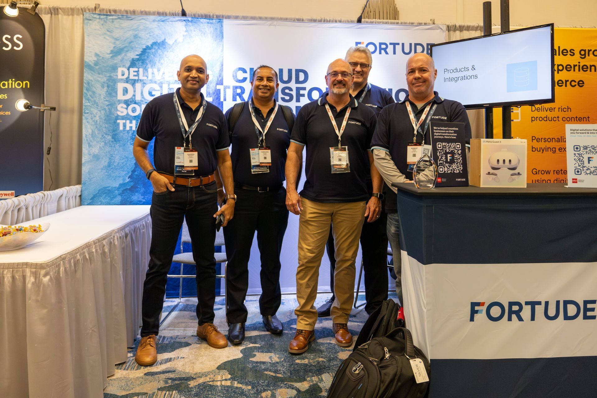 Five men in matching shirts stand at a Fortitude booth, smiling for a photo.