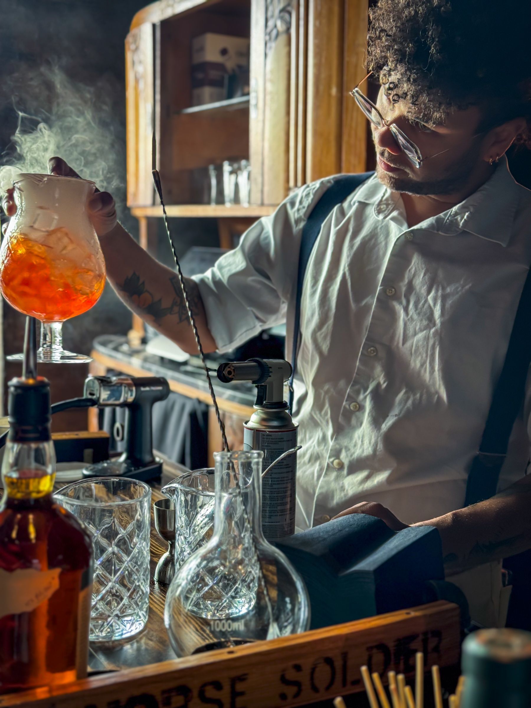 Bartender pouring a colorful cocktail into a glass. Vintage bar setting.