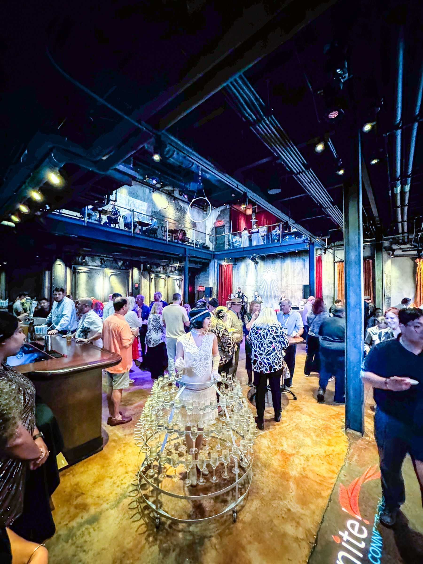 Event in a large industrial-style space with people mingling. Large, artful metal sculpture in the foreground.