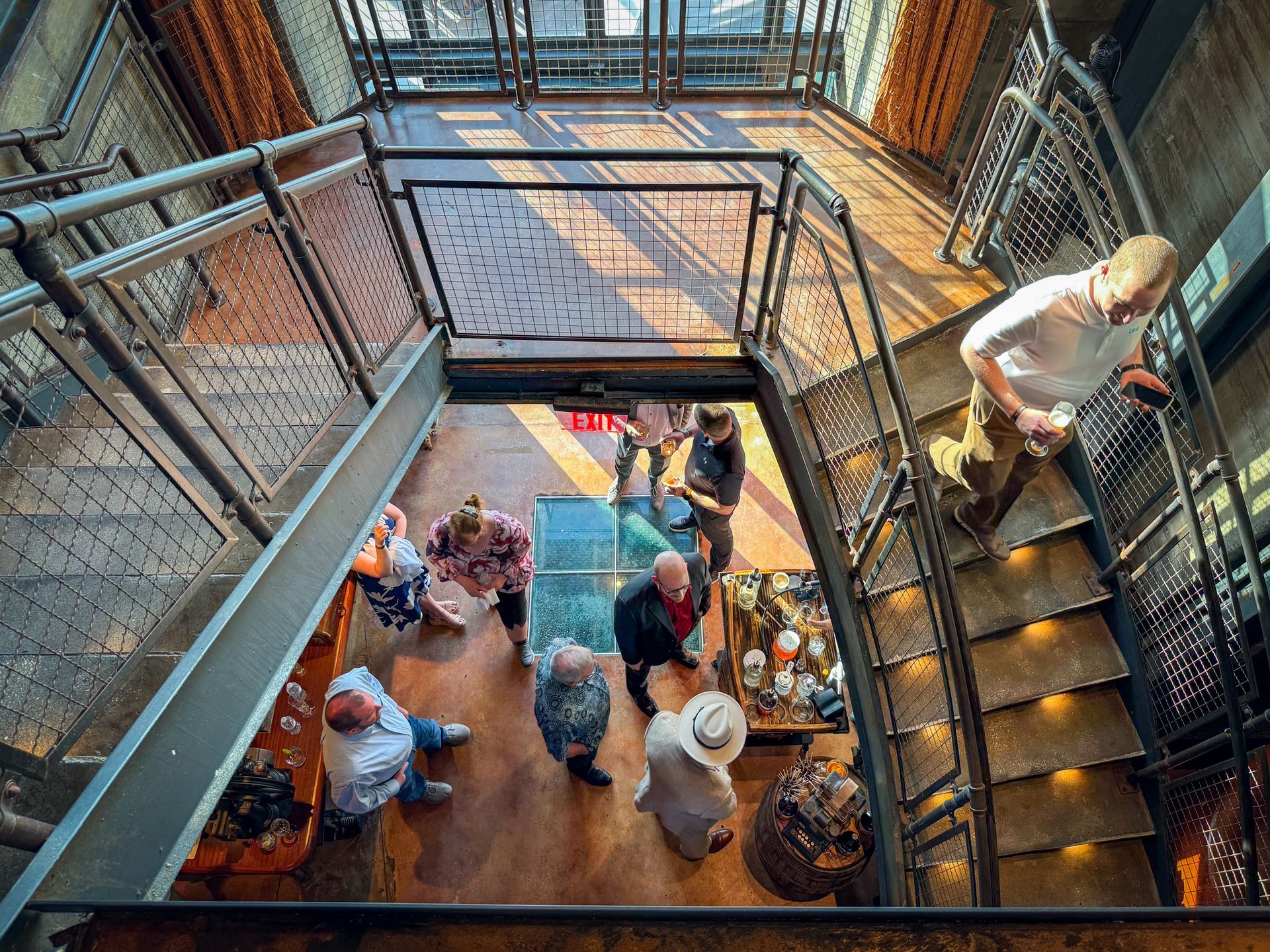 People on metal stairs and platform, looking down. Interior shot with industrial design.