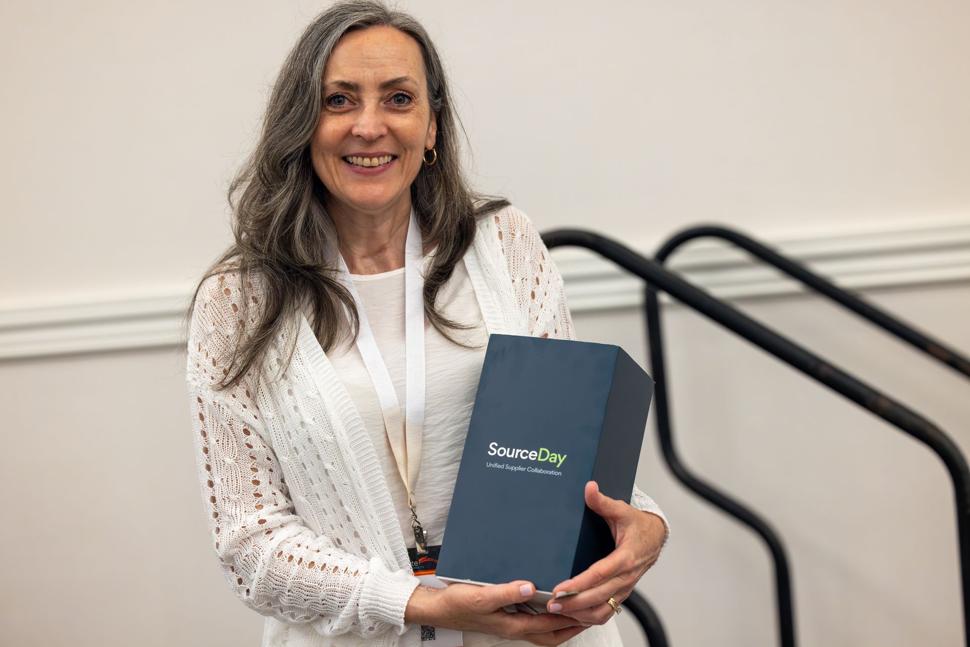 Woman smiles, holding a blue box labeled 