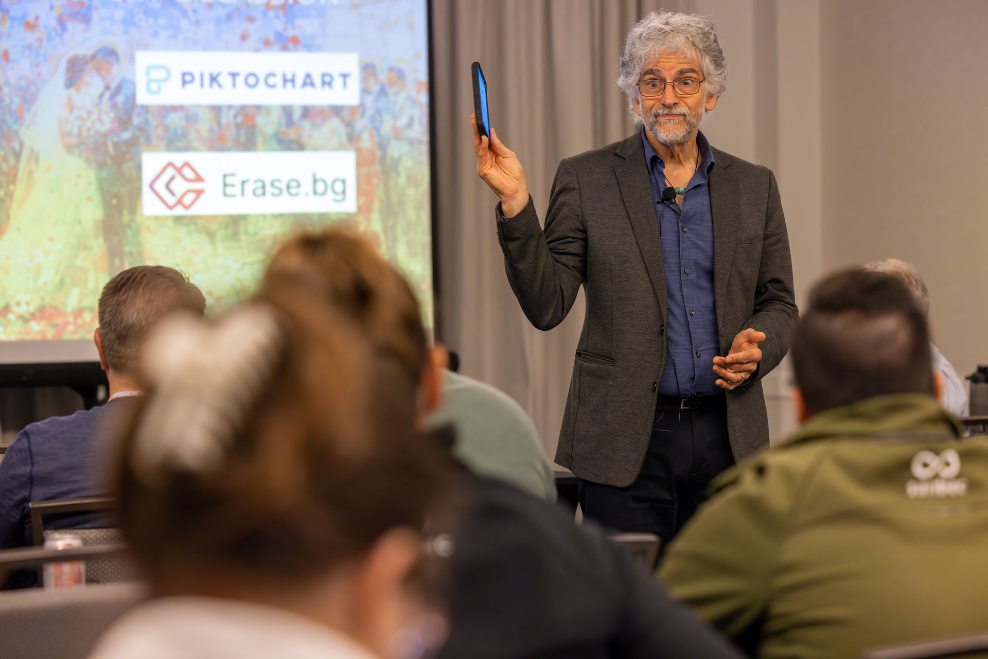 Man presenting with phone in hand, pointing at projector screen showing 