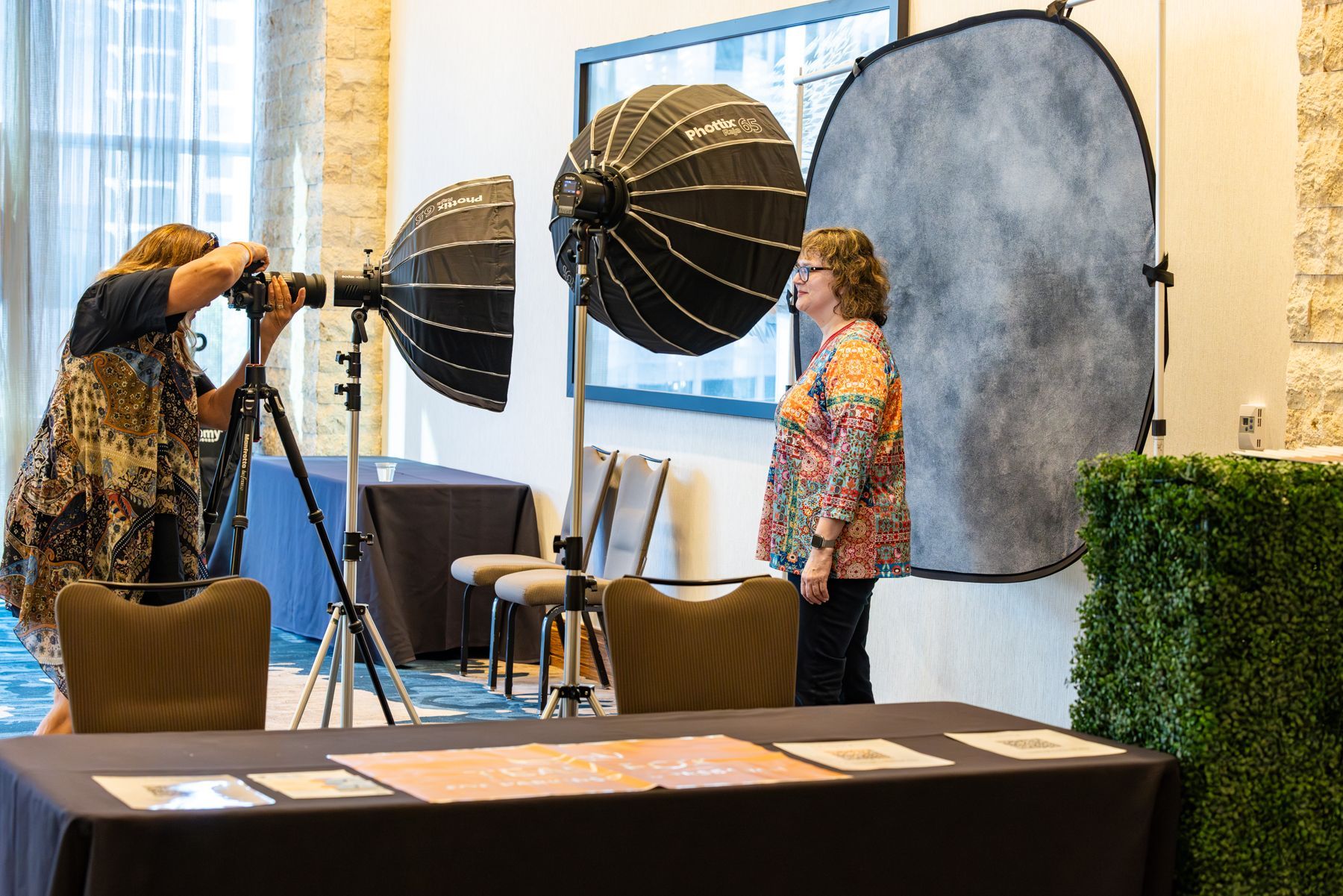 Photographer taking photo of woman under studio lights, indoor setting.