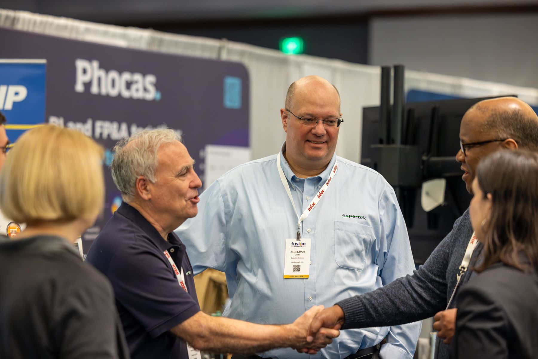 People shaking hands at a conference booth with 
