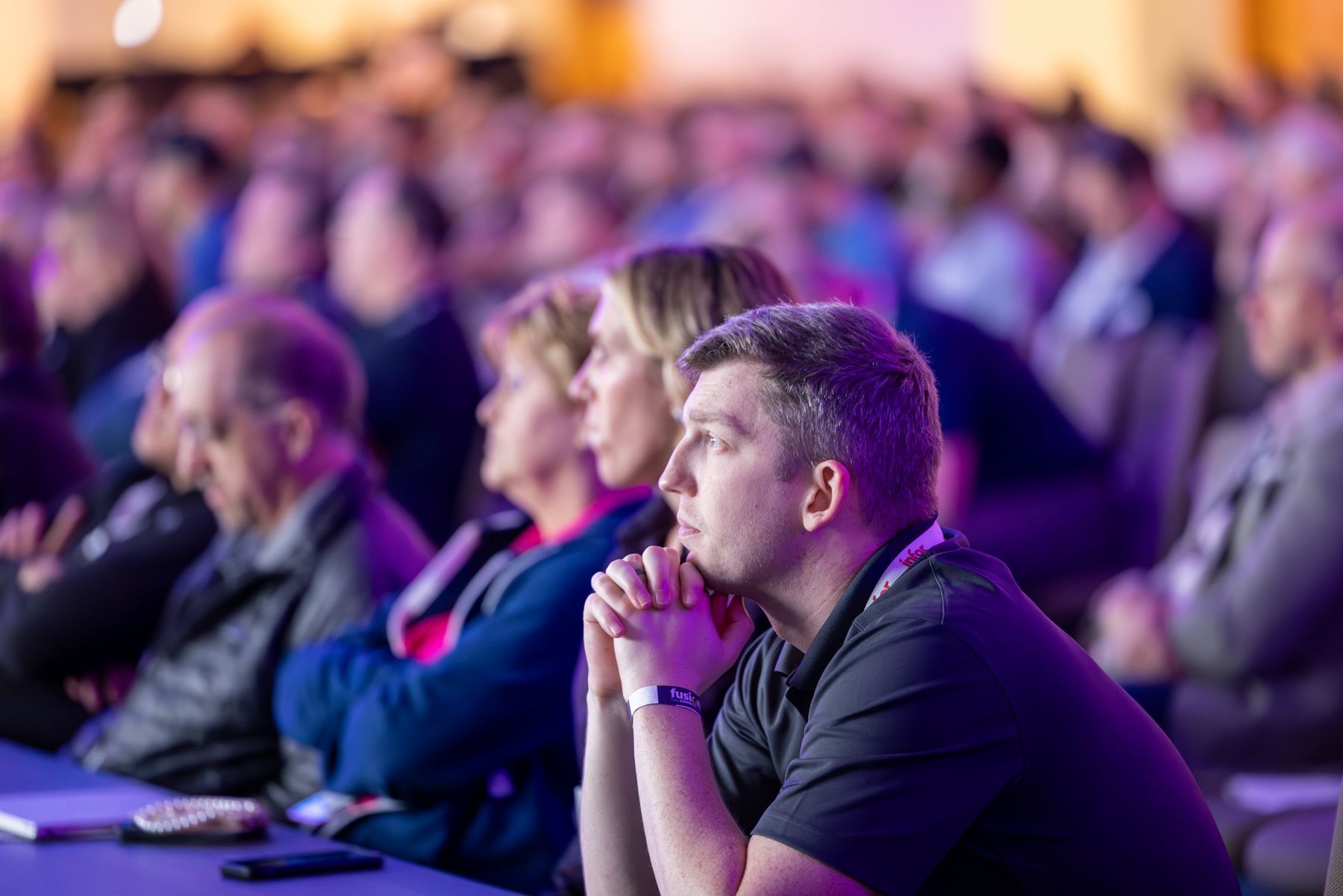 Audience at a conference, focused, many rows, dim lighting.