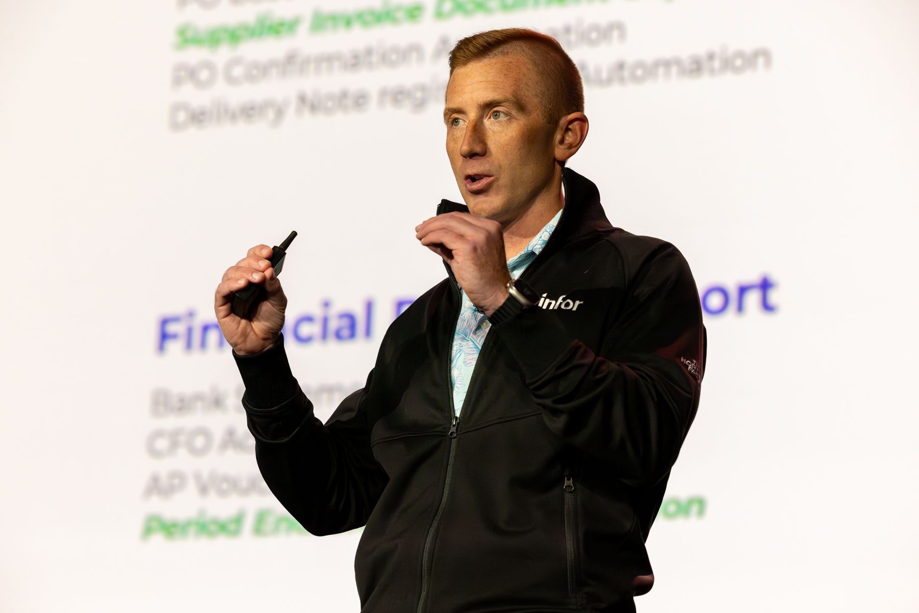 Man presenting financial report details with a pointer, in front of a screen with text.