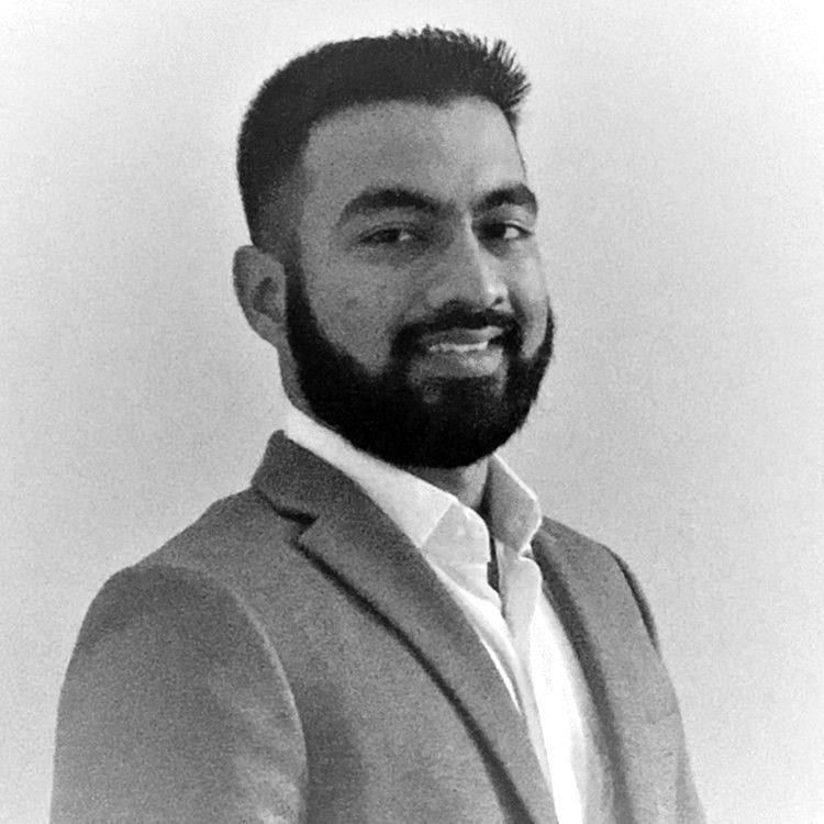 Man with a beard, wearing a suit jacket and dress shirt, smiling.