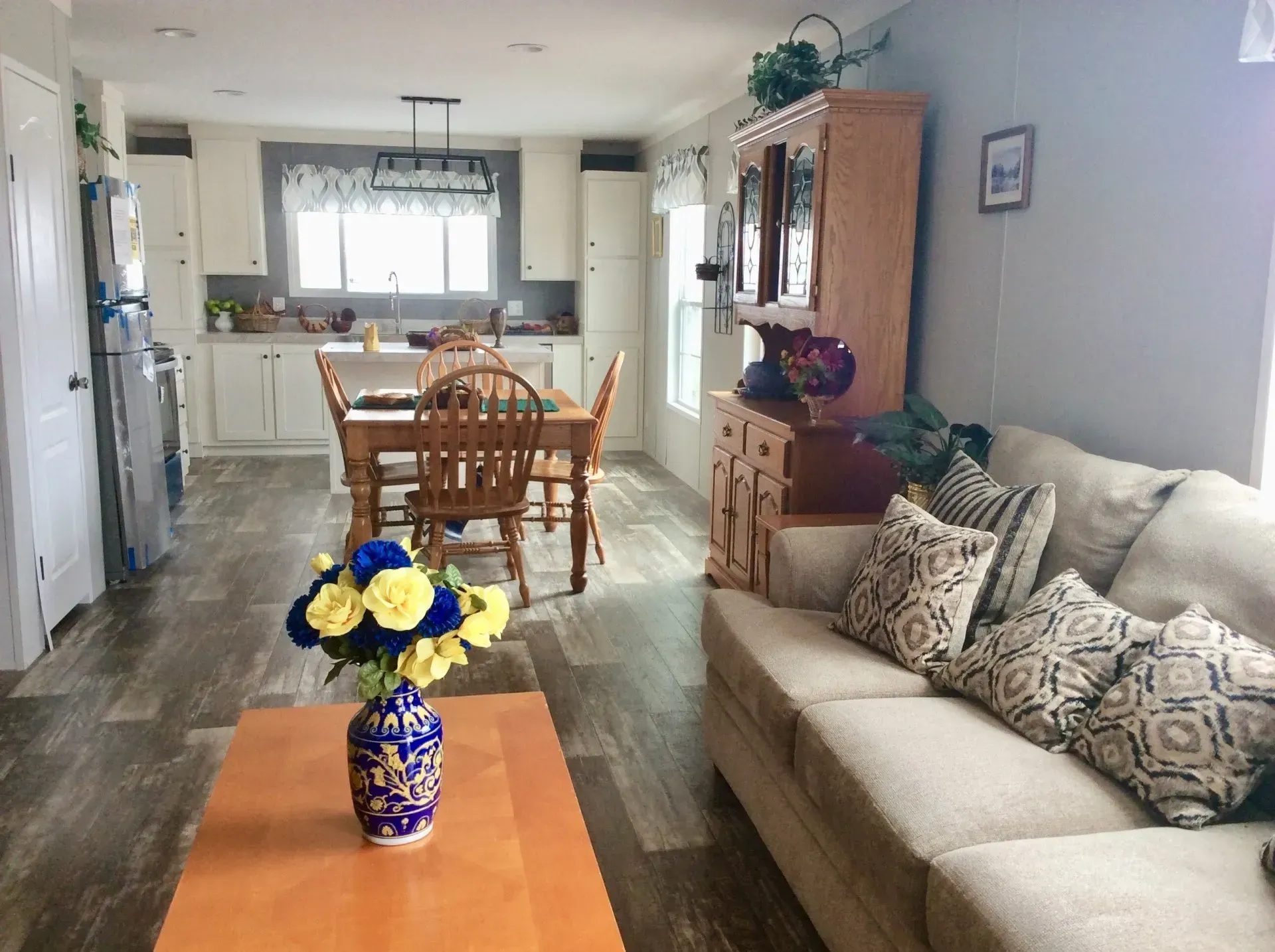 A living room with a couch , table , chairs and a vase of flowers on the coffee table.