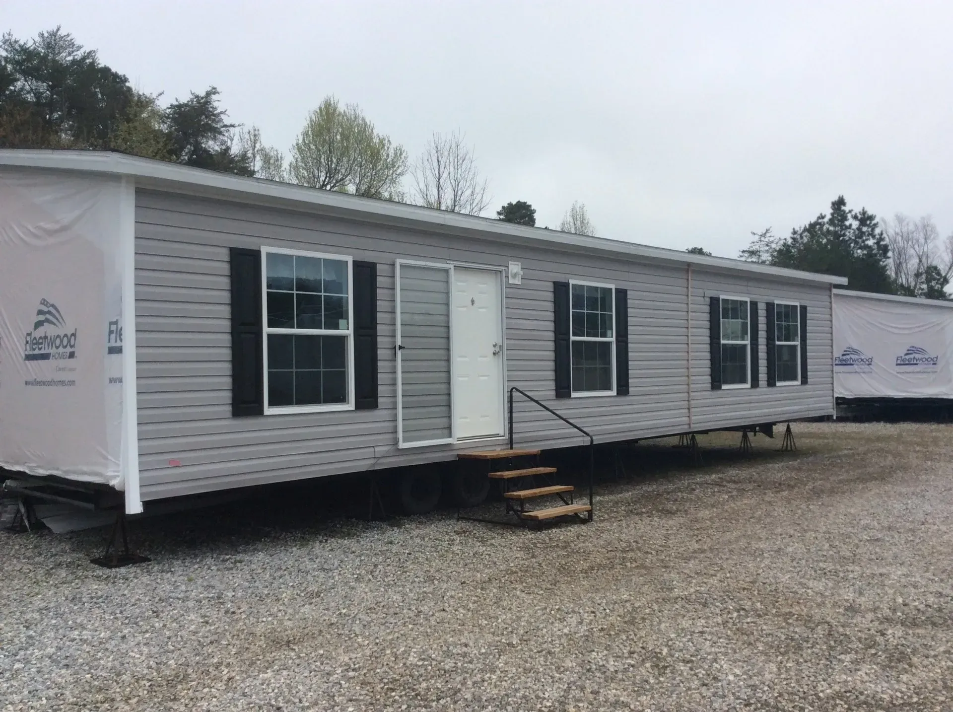 A mobile home is parked in a gravel lot.
