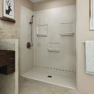 A beige accessible shower with multiple built-in shelves.