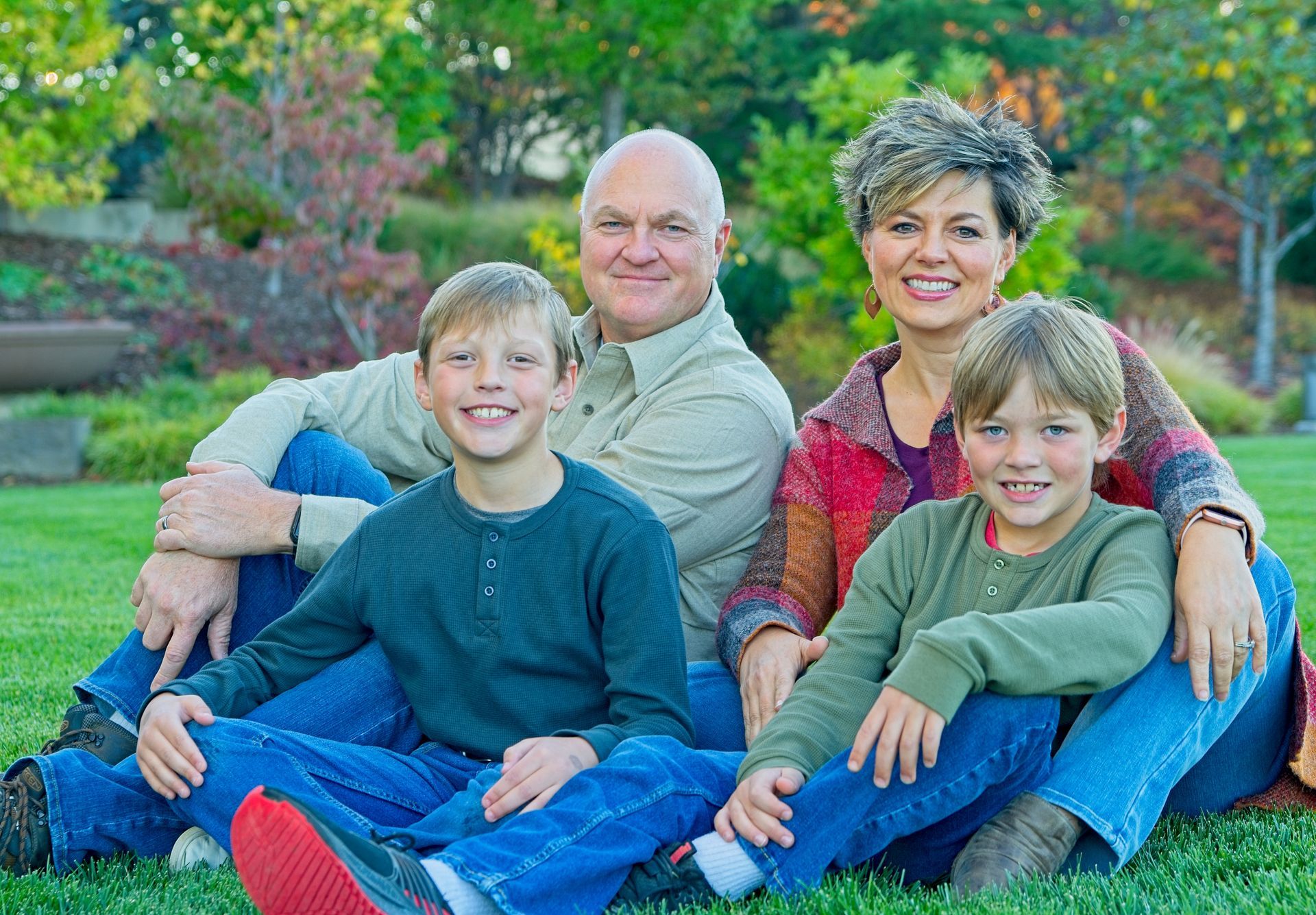 A family is posing for a picture while sitting on the grass.