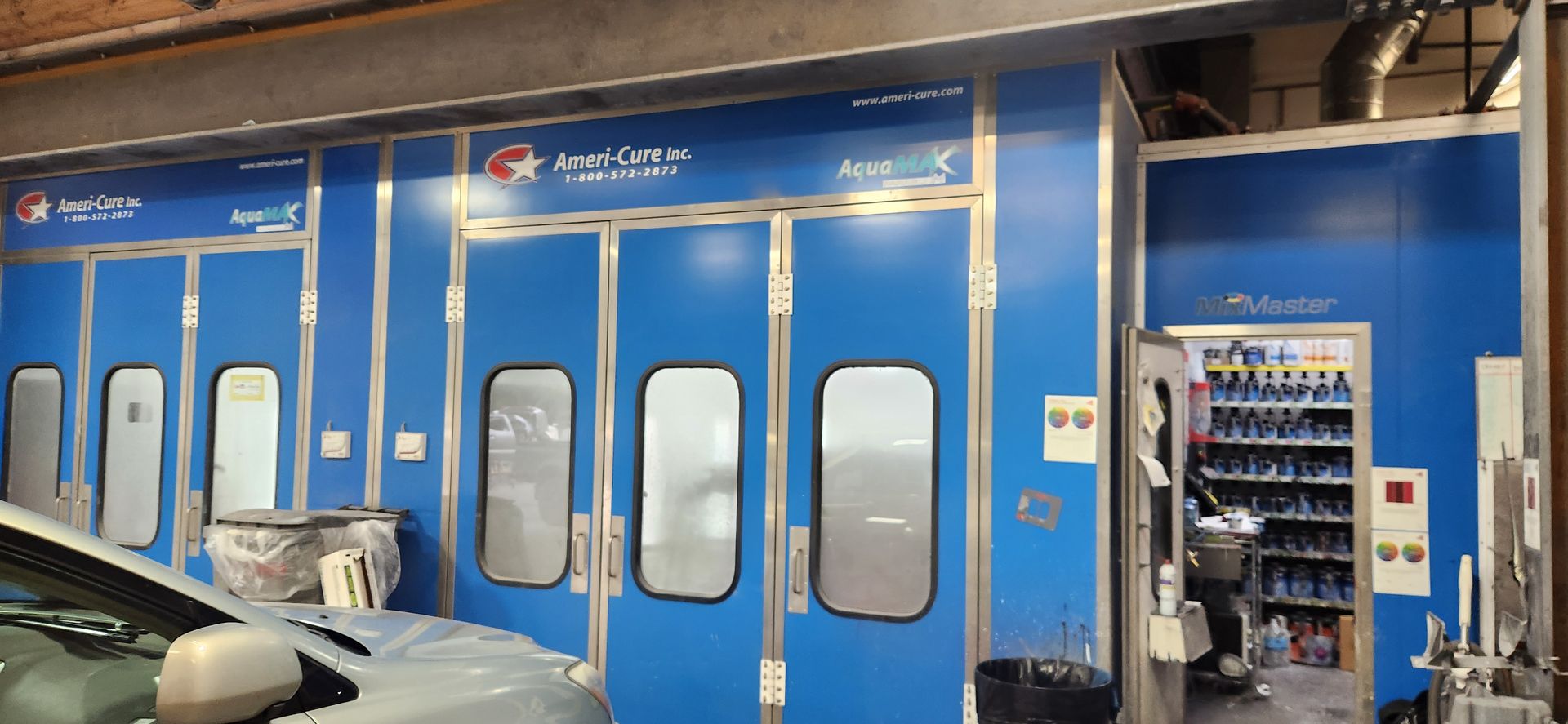 Blue auto body paint booth with multiple spray bays and a car in the foreground | Tripp's Auto Body