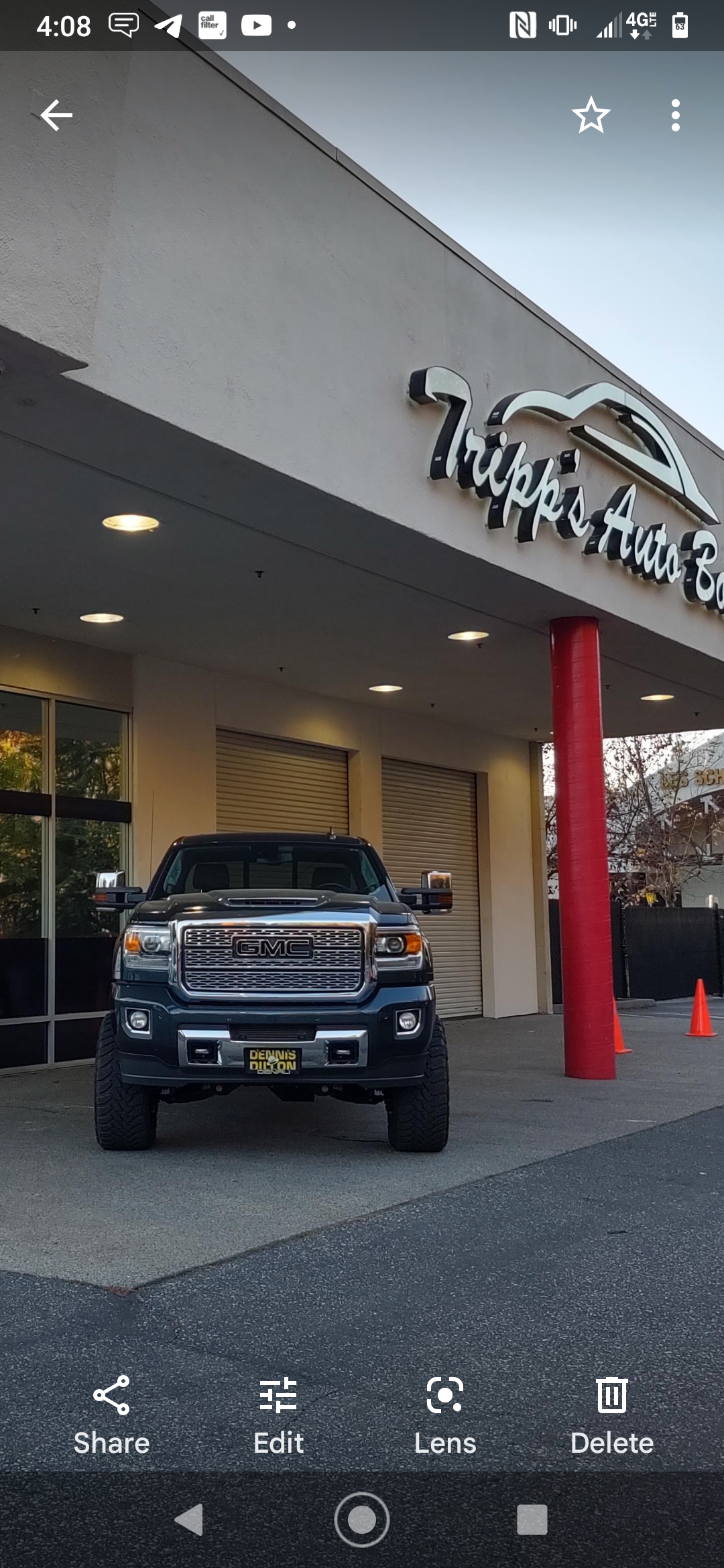 Black SUV parked under a dealership awning with a “Tire Mart” sign above. | Tripp's Auto Body