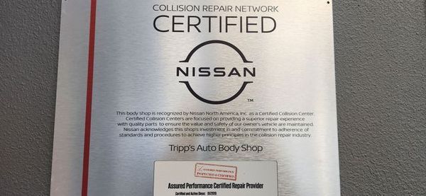 Certified Nissan collision repair network sign with red border on a wall. | Tripp's Auto Body