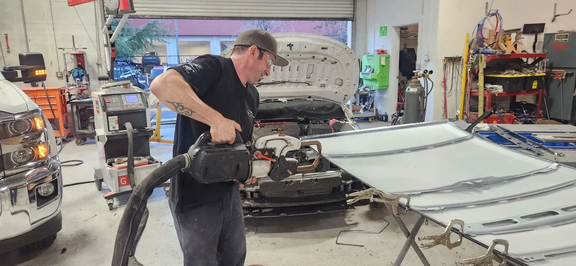 Man vacuuming the interior of a car in a busy auto repair garage | Tripp's Auto Body