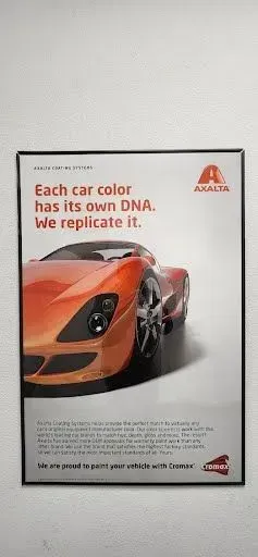 Poster of an orange sports car with text: “Each car color has its own DNA. We replicate it.” | Tripp's Auto Body
